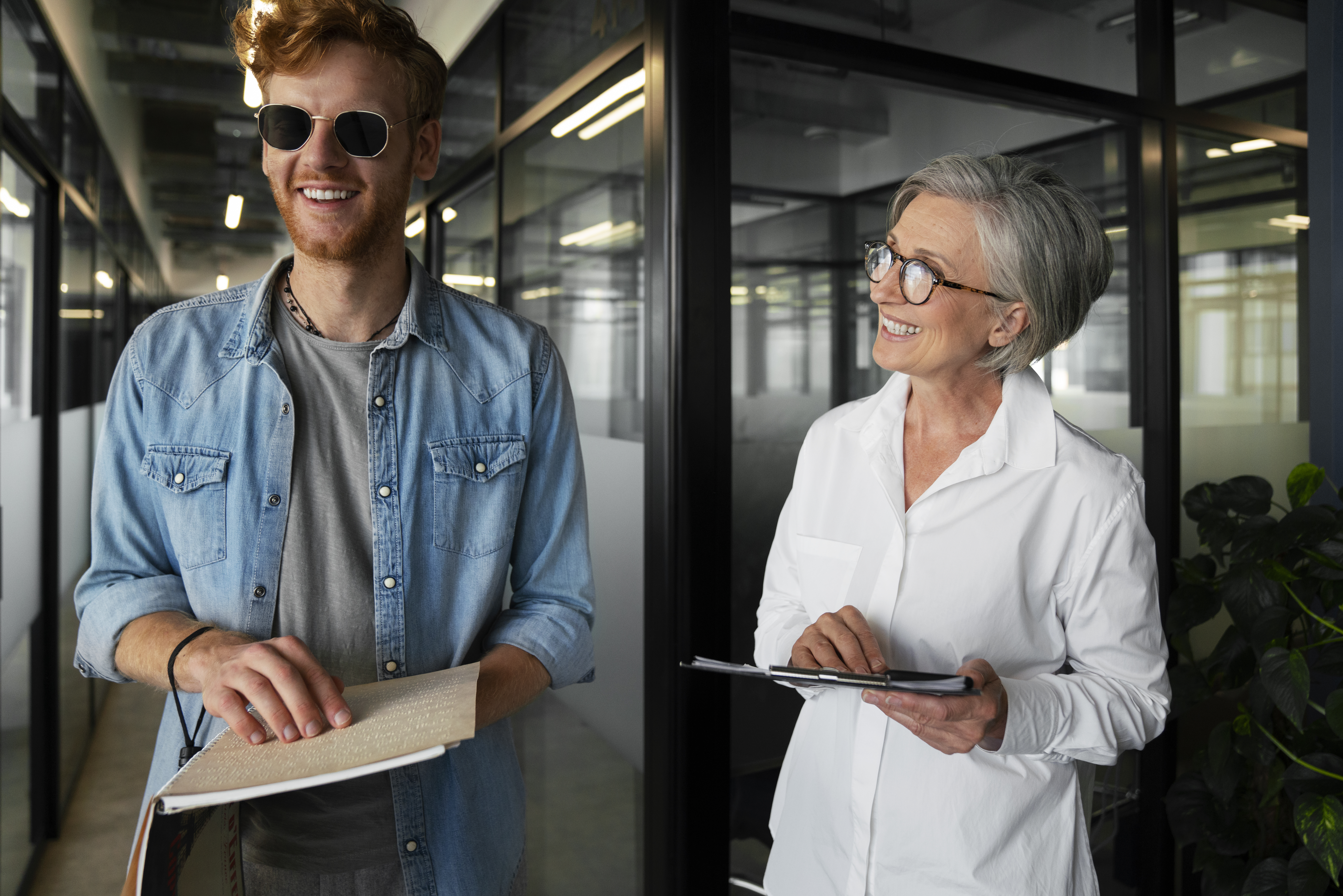 A blind person reading braille and a woman smiling next him