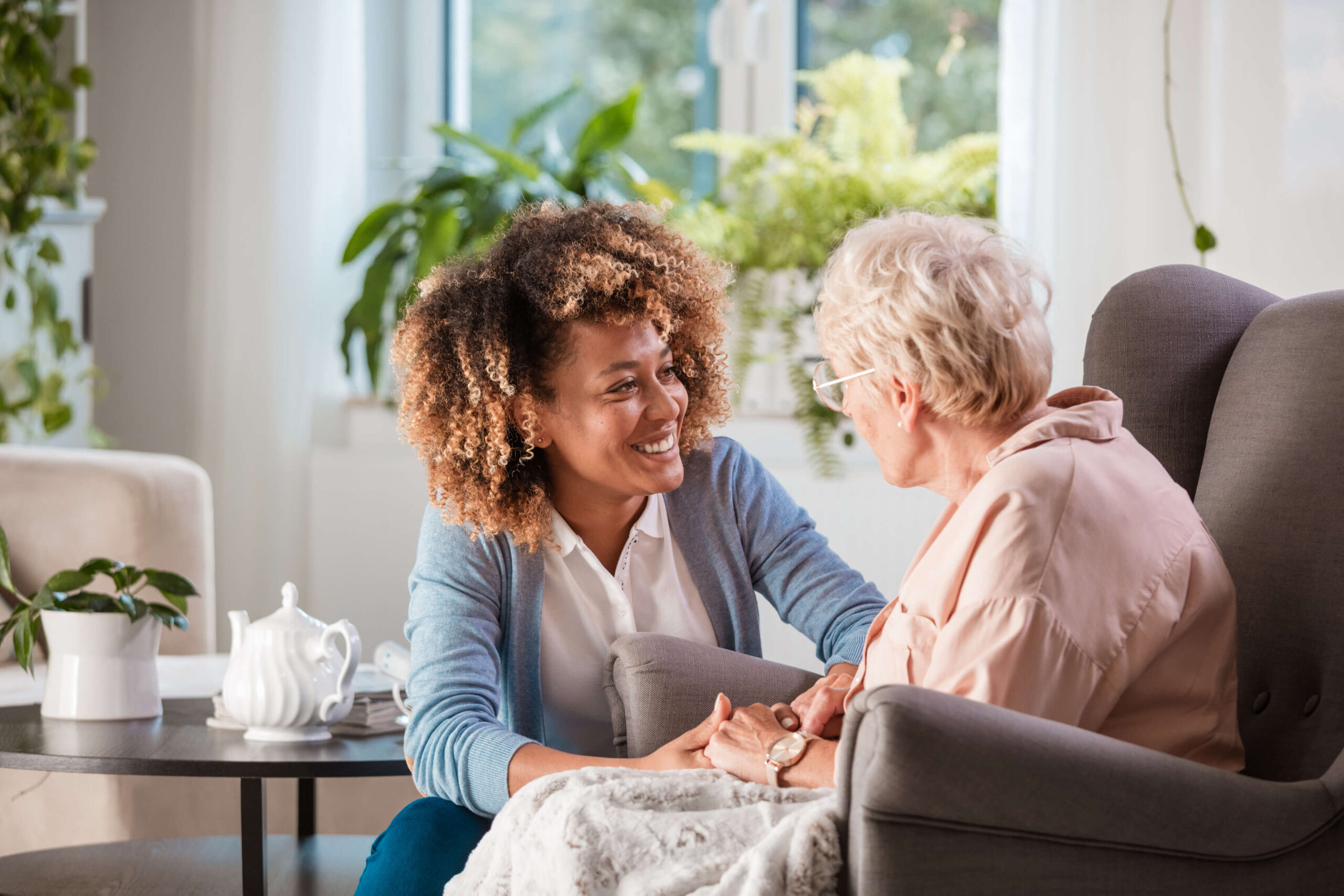 Woman with curly hair smiling at elderly woman