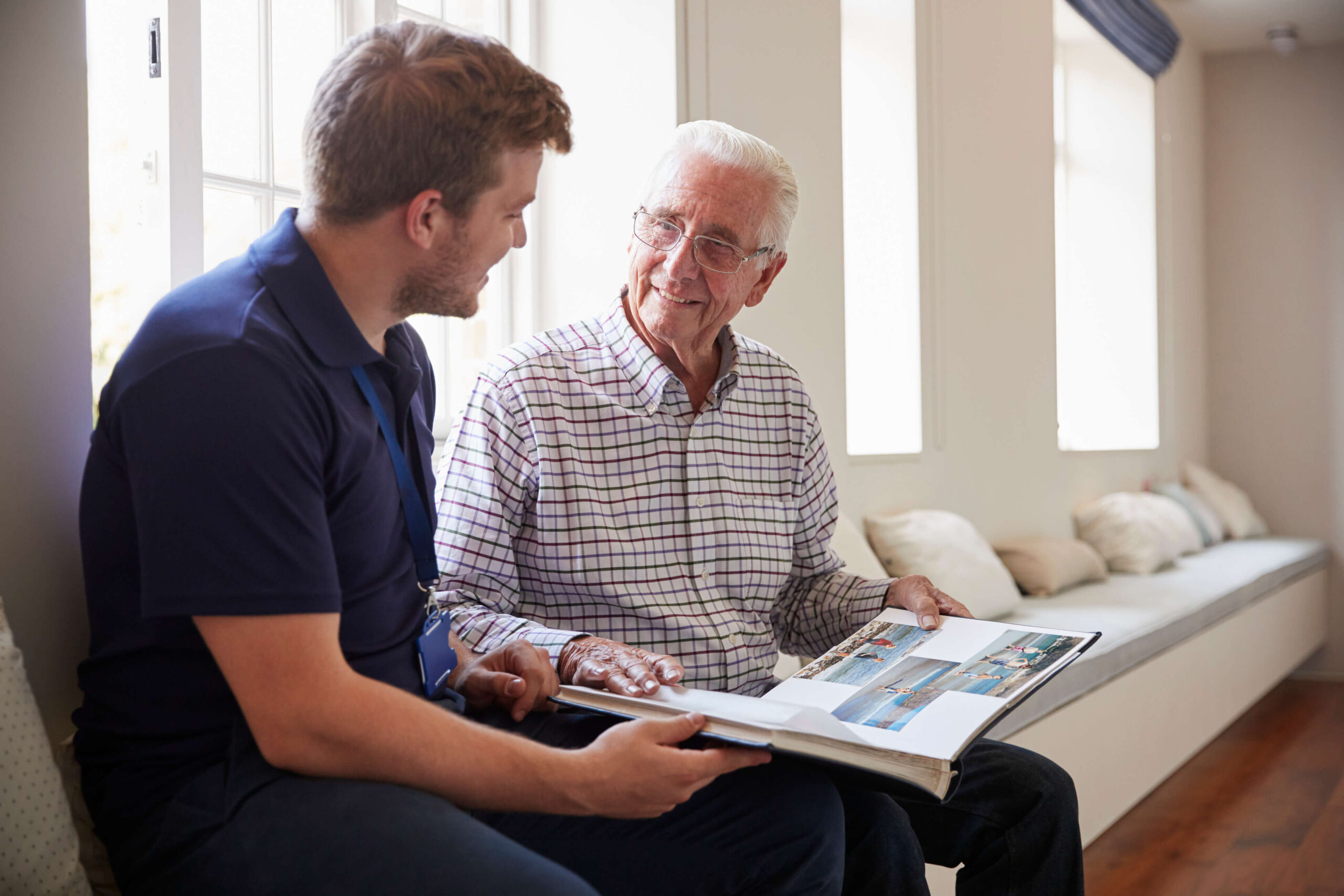 Man speaking to elderly man with photo album