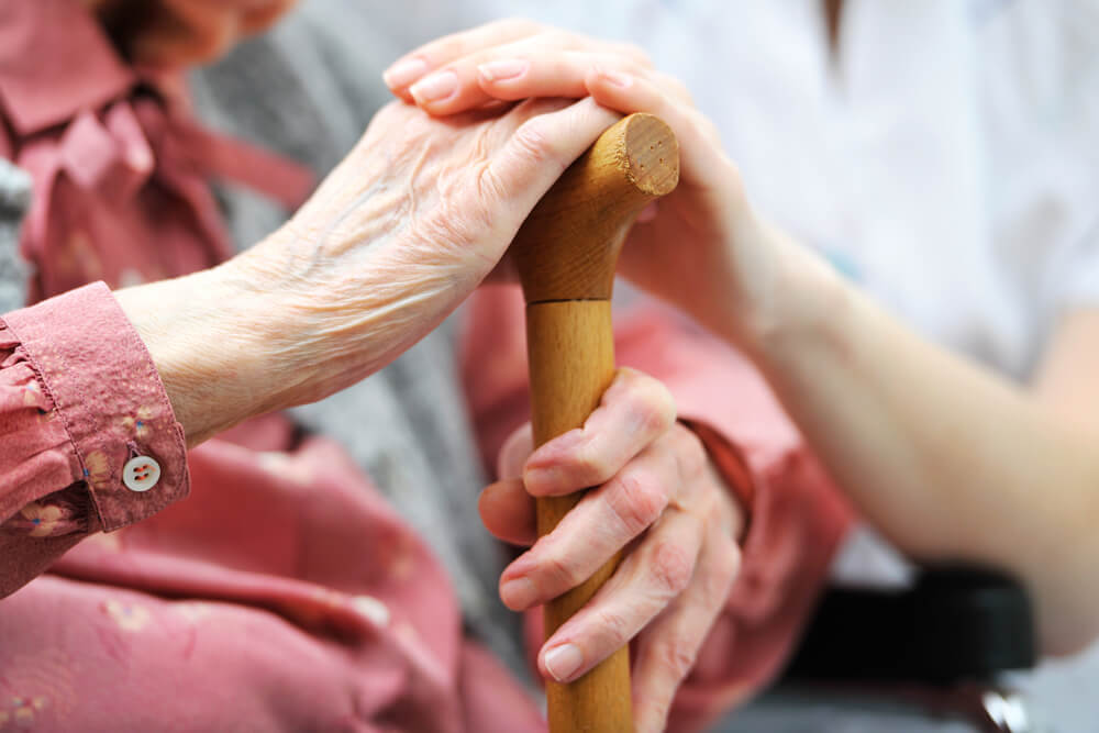 HCP support worker holding elderly person's hand during home care packages service